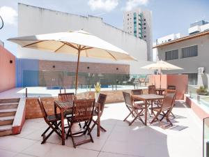 un patio con mesas, sillas y una sombrilla en OYO Alto Da Praia Hotel, Aracaju, en Aracaju