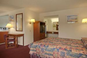 a hotel room with a bed and a desk at Days Inn by Wyndham Fresno South in Fresno