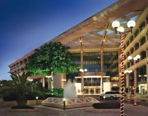 a large building with a fountain in front of it at Mövenpick Grand Al Bustan in Dubai