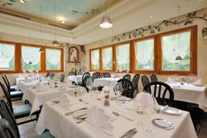 un restaurante con mesas y sillas blancas y ventanas en Hotel Ahorni, en Oberwald