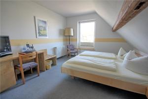 Dormitorio con cama, escritorio y TV en Lechstedter Obstweinschänke en Bad Salzdetfurth