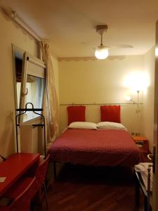 ボローニャにあるB&B Via del Carroのベッドルーム1室(赤いシーツとランプ付きのベッド1台付)