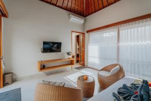 sala de estar con sillas de mimbre y TV en Arta Private Villa, en Ubud