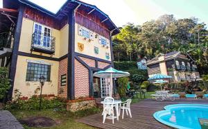 a house with a deck next to a swimming pool at Nova Pousada Chamonix in Teresópolis