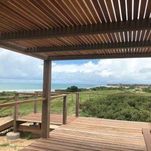 a wooden deck with a bench and a wooden roof at Beach Wind Hotel in Flecheiras