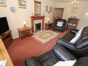 a living room with a leather couch and a fireplace at Penelope in Benllech
