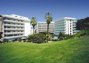 a park with palm trees in front of a building at Hotel Gran Garbi & AquaSplash in Lloret de Mar