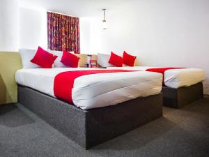 a bedroom with a large bed with red pillows at OYO Hotel Oasis, Matehuala in Matehuala