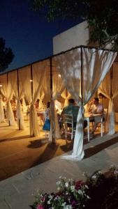 grupa ludzi siedzących przy stolikach pod namiotem w obiekcie Tenuta Sidore w mieście Cursi