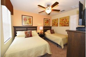 a bedroom with two beds and a ceiling fan at Holiday Villas of Davenport in Davenport