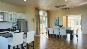 a kitchen and dining room with a table and white chairs at Villa Panda at C Links Golf Resort in Mui Ne