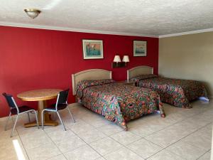 una habitación de hotel con dos camas y una mesa en Economy Inn, en Arcadia