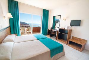 een hotelkamer met een bed, een bureau en een raam bij Hotel Gran Garbi Mar & AquaSplash in Lloret de Mar