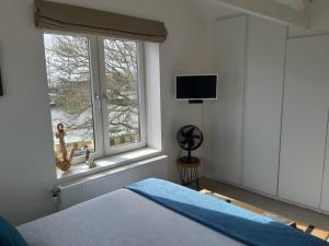 een slaapkamer met een bed en een raam met een televisie bij Appartement Havenzicht in Enkhuizen
