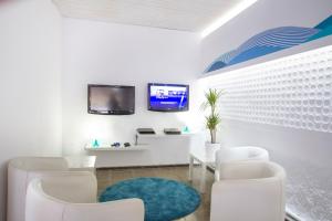 una sala de espera con sillas blancas y TV en Hotel Villa Garbí, en Lloret de Mar