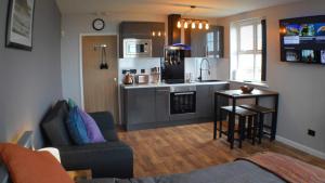 The Den Studio Apartment - Withernsea في ويذرنسه: مطبخ وغرفة معيشة مع أريكة وطاولة