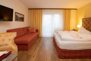 Habitación de hotel con cama y sofá en Landhotel Agathawirt en Bad Goisern