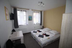 a bedroom with two beds and a desk and two windows at Penzion u Blanice in Husinec
