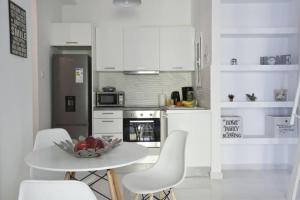 uma cozinha branca com uma mesa e cadeiras brancas em Victoria Sq., A cozy and stylish apartment em Atenas
