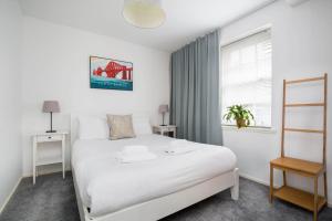 a bedroom with a white bed and a window at Modern Grassmarket Apartment in Edinburgh