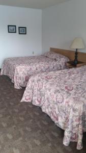 2 camas en una habitación de hotel con sábanas rosas en Rimbey Motor Inn, en Rimbey