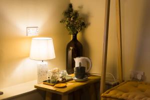 una mesa con una lámpara y un jarrón con flores. en Exelby Green Dragon en Leeming Bar