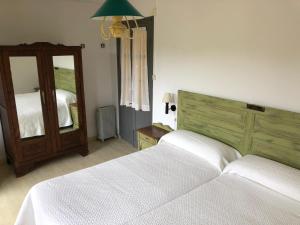 1 dormitorio con 2 camas blancas y espejo en CASA RURAL DOSAL, en Ruiseñada