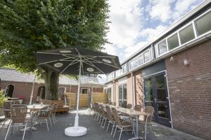 een patio met tafels en stoelen en een parasol bij B&B bij de 3 linden in Wijchen