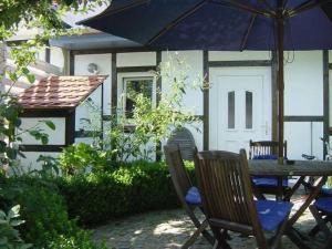 - une table et des chaises avec un parasol en face d'une maison dans l'établissement Haus Alexandrine, à Warnemünde