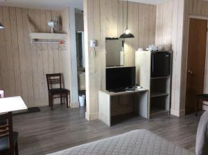 a living room with a refrigerator and a table with a television at Motel du Bic in Bic