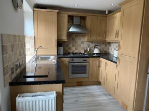 a kitchen with wooden cabinets and a stove top oven at Castle Cottage in Harrogate