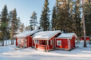 una casa roja con nieve en el techo en la nieve en Lomaperkkiö Cottages en Kajaani