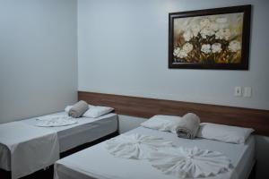 two beds in a room with a picture on the wall at Tangará Hotel in Paraíso do Tocantins