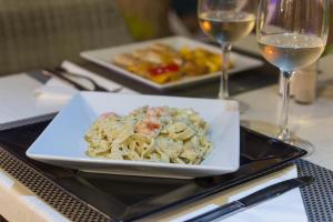 a plate of pasta on a table with wine glasses at Alcudia Petit - Turismo de Interior in Alcudia