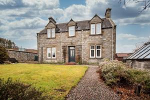 an old stone house with a grass yard at Convalmore House in Dufftown