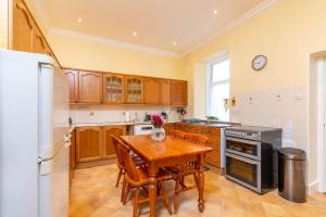 een keuken met een tafel en stoelen en een koelkast bij Convalmore House in Dufftown