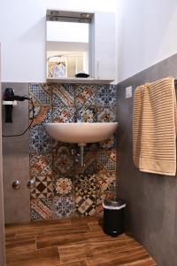 a bathroom with a sink and a mosaic wall at Il mito in Castellaneta