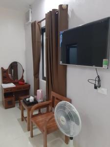 a living room with a flat screen tv and a fan at Van Anh Motel in Cốc Lếu