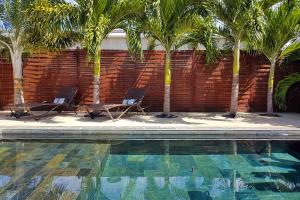 two chairs and palm trees next to a swimming pool at Villa Oasis in Faaa