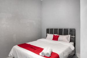 a white bed with red and white towels on it at RedDoorz near Manhattan Square Medan in Pulauberayan