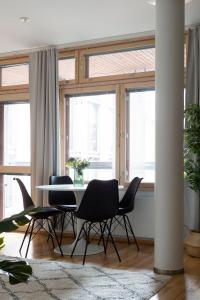 a dining room with a table and chairs and windows at 2ndhomes Deluxe 1BR Kamppi Center Apartment with Sauna and Terrace in Helsinki