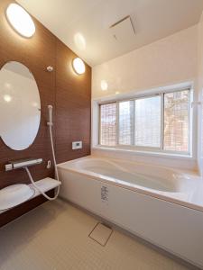 bagno con vasca, servizi igienici e specchio di ゲストハウス メグルヤ 中山道柏原宿 a Maibara