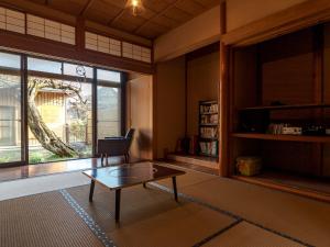a living room with a coffee table and a large window at ゲストハウス メグルヤ 中山道柏原宿 in Maibara