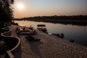 un gruppo di panchine sedute accanto a un fiume di Hakusembe River Campsite a Rundu