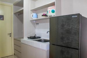 a small kitchen with a sink and a refrigerator at Minimalist Studio Apartment with City View at M-Town Residence By Travelio in Tangerang