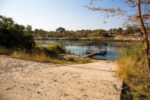 een boot op een rivier naast een onverharde weg bij Hakusembe River Campsite in Rundu