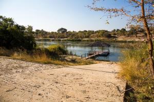a boat on a river next to a dirt road at Hakusembe River Campsite in Rundu