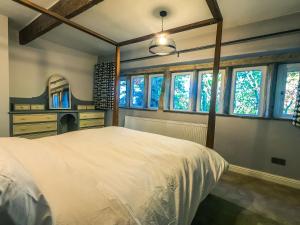 a bedroom with a large white bed and windows at Luxury traditional stone farmhouse in Saddleworth in Oldham