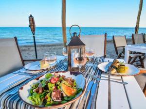 a table with plates of food and wine glasses on the beach at Thracian Cliffs Owners Apartments in Kavarna