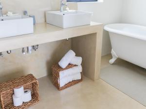 a bathroom with a sink and a bath tub and towels at 401 Rozendal Cottages in Stellenbosch +54 photos